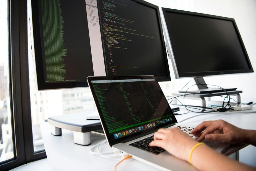 Developer working on multiple screens, representing nearshore development Europe and AI-driven software engineering