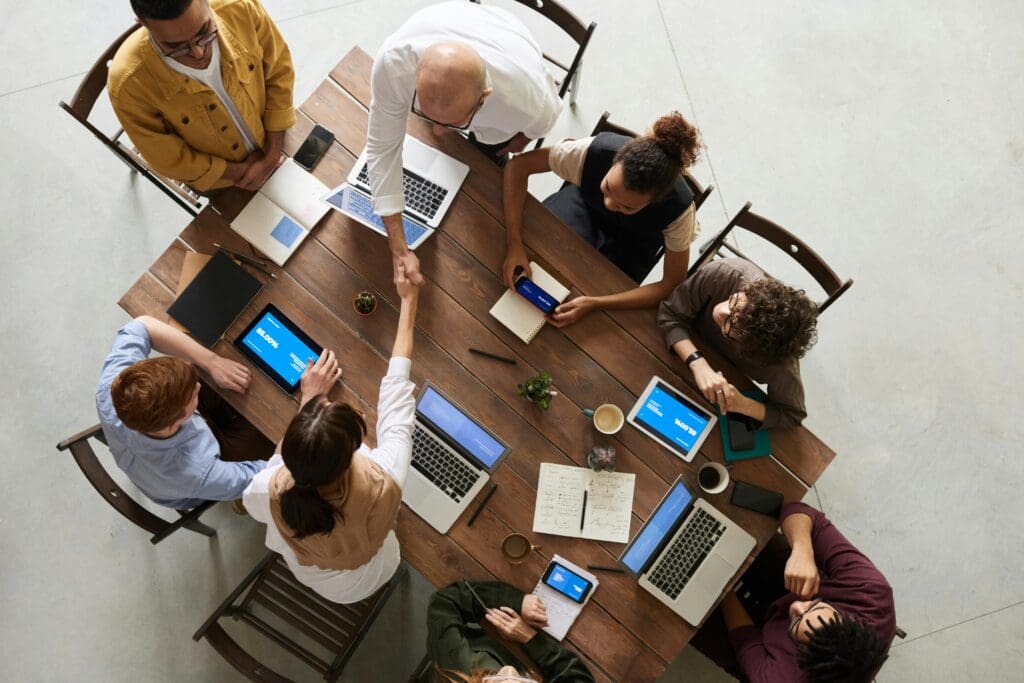 Agile tech team collaborating around a table with laptops and tablets in a modern office