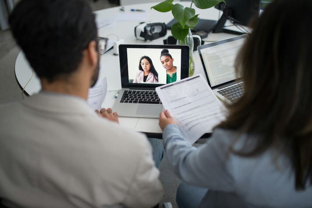 Remote team collaboration through video call with developers reviewing documents and working together
