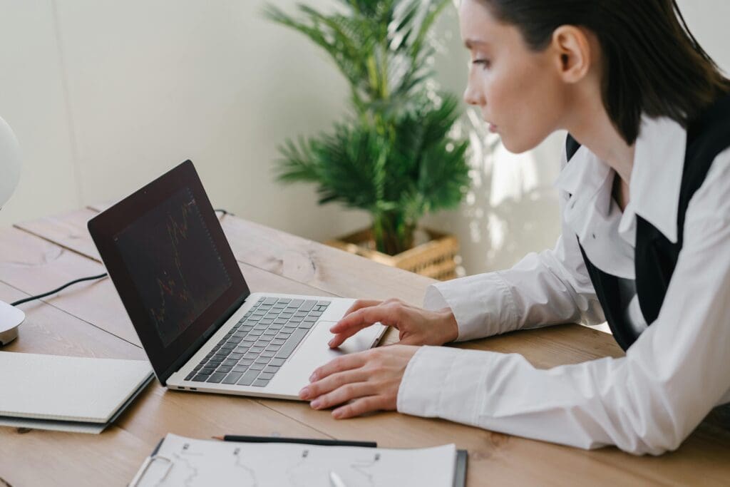 Person analyzing European tech trends on a laptop with financial charts at a desk