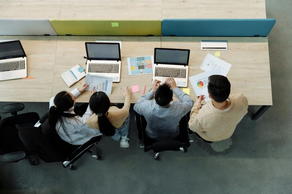 Scaling SaaS teams collaborating in a modern office, reviewing data charts and analytics on laptops during a team strategy meeting.